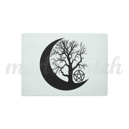 Decorative glass cutting board with a black silhouette of a tree within a crescent moon and pentagram symbol on a white background.  Perfect for witches and wiccans